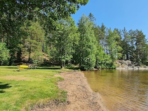 A lakeside park with a bench, trees, and a clear view of the water.