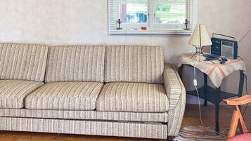 A living room with a sofa, a small table with a lamp, and a chair.