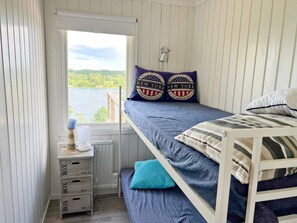 Enjoy a serene lake view from this bedroom featuring a bunk bed and a single bed, each with its own unique pillows.