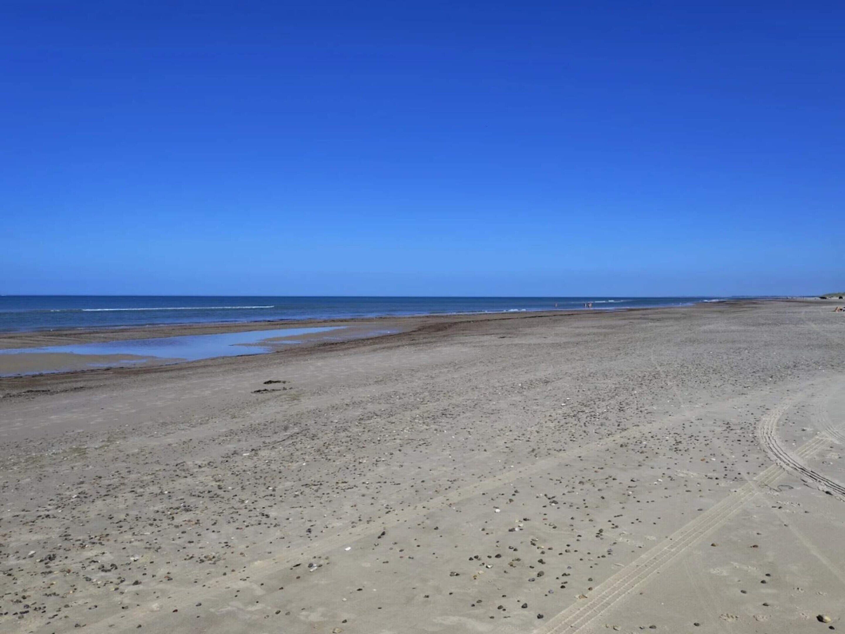 Una ampla platja de sorra amb un cel blau i clar.