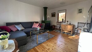 A cozy living room with a grey sofa, a wooden coffee table, and a fireplace. - 4 Person Holiday Home in Hillerstorp-by Traum (Hillerstorp)