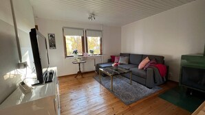 A living room with a wooden floor, a grey sofa, a coffee table, and a TV on a stand. - 4 Person Holiday Home in Hillerstorp-by Traum (Hillerstorp)