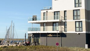 A modern building with a flat roof, multiple balconies, and a sign indicating a restaurant.