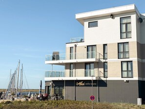 Un bâtiment moderne doté d’un toit plat, de nombreux balcons et d’une enseigne indiquant la présence d’un restaurant.