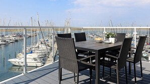 A dining area with a table and chairs overlooking a marina with numerous boats.