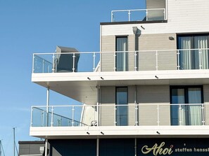 Un immeuble à plusieurs étages doté de balcons, de grandes fenêtres et d’une enseigne bien visible avec du texte.