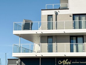 A multi-story building with balconies, large windows, and a visible sign with text.