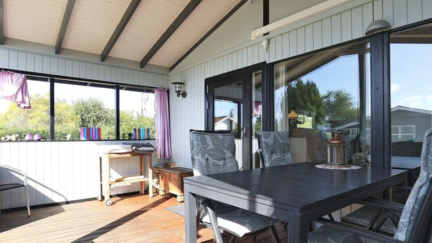 A covered patio with a table and chairs, large windows, and a view of the outdoors. - 6 Person Holiday Home in Karrebaeksminde-by Traum (Karrebæksminde)