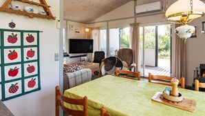 A cozy living room with a wooden ceiling, a TV, a fireplace, and a dining area with a table set for two. - 6 Person Holiday Home in Karrebaeksminde-by Traum (Karrebæksminde)