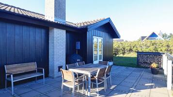 A patio with a table and chairs, a bench, and a covered grill area.