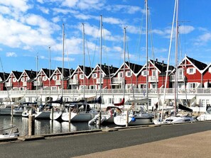 A marina with red and white buildings, boats docked, and a clear sky. - 5 Star Holiday Home in Bagenkop (Sydlangeland)