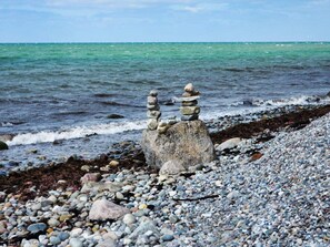 Eine felsige Küstenlinie mit einem Felsen und einem Kiesstrand.