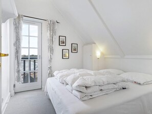 Ein Schlafzimmer mit einem Bett, einem Fenster mit Vorhängen und einer Wandleuchte.