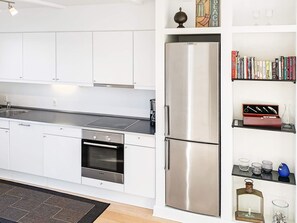 A modern kitchen with white cabinets, a stainless steel refrigerator, and a built-in oven. - 5 Star Holiday Home in Bagenkop (Sydlangeland)