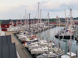 A marina with multiple boats docked, a red building with white trim, and a church in the background. - 5 Star Holiday Home in Bagenkop (Sydlangeland)