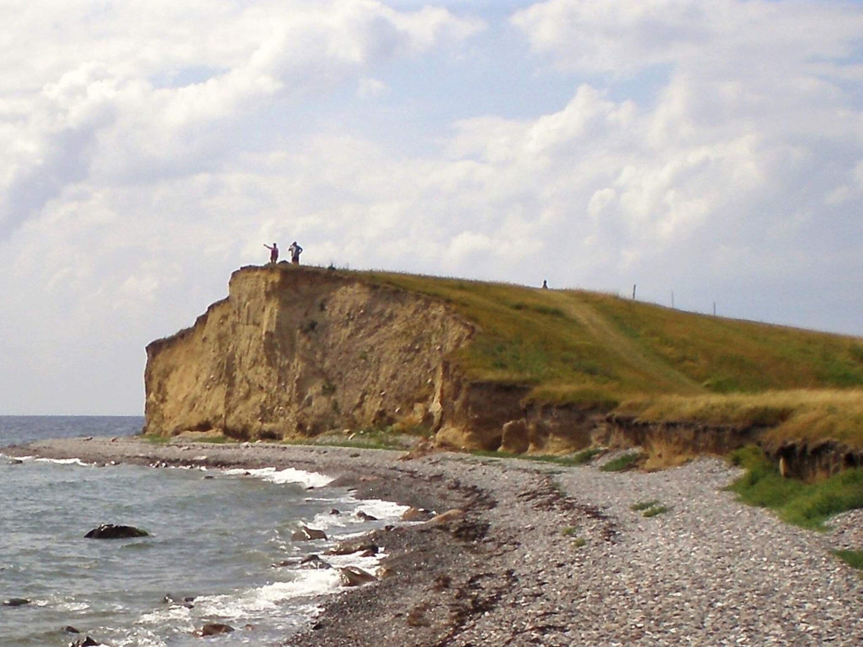 Een kustlandschap met een rotsachtige kust, een grasachtige klif en de oceaan.