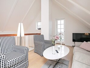 Un salon moderne avec un canapé à motifs à carreaux, une table basse ronde et un téléviseur.