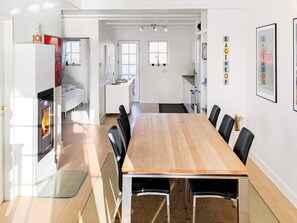Une cuisine moderne avec des armoires blanches, un four encastré et un coin repas comprenant une table et des chaises en bois.