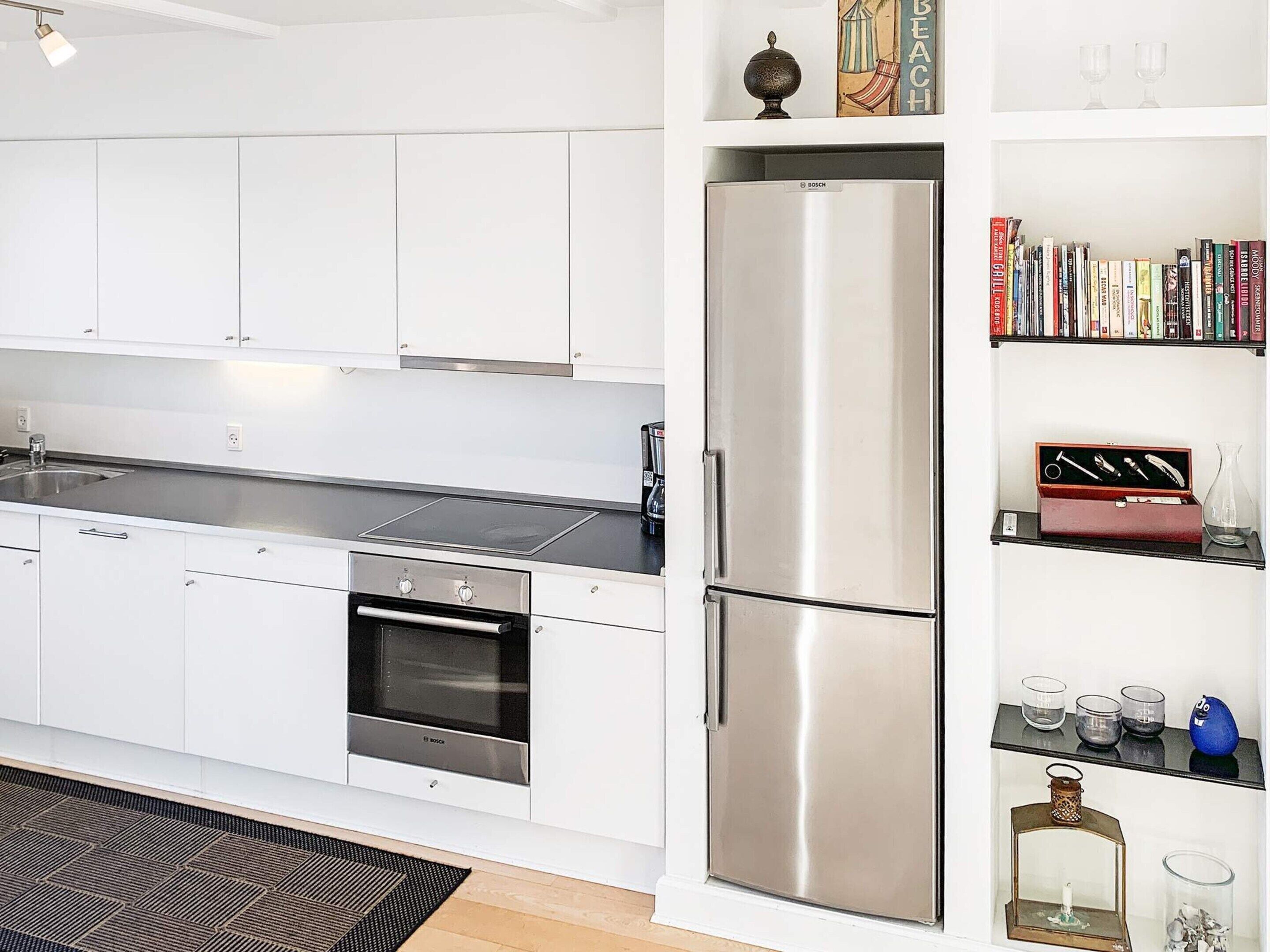 Eine moderne Küche mit weißen Schränken, einem Edelstahl-Kühlschrank und einem eingebauten Backofen.