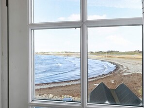 Ein Fenster mit Blick auf einen Strand und Wellen.