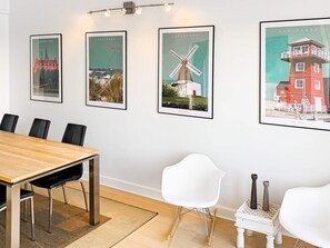 Een vergaderruimte met een houten tafel, zwarte stoelen en lijstwerken aan de muur.