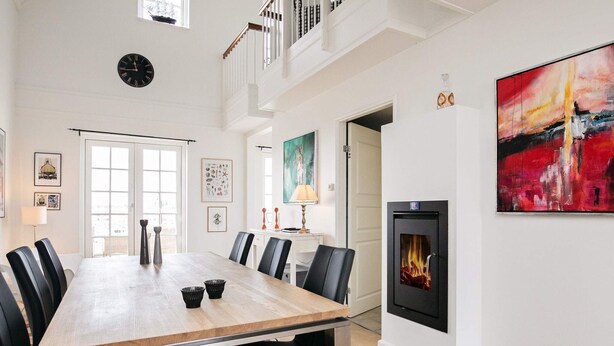 Une salle à manger spacieuse avec une longue table, des chaises noires et une cheminée moderne.