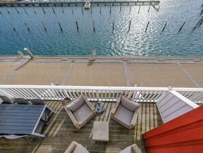 A deck with outdoor seating, a view of the water, and a dock in the background.