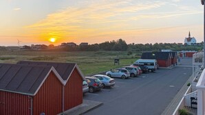 Un parking rempli de voitures, un bâtiment rouge et une église en arrière-plan.