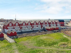 Une rangée de bâtiments rouges et blancs, avec un quai et une zone herbeuse devant.