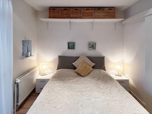 A bedroom with a large bed, two bedside tables with lamps, a radiator, and a shelf above the bed. - 4 Star Holiday Home in Lokken (Lokken)