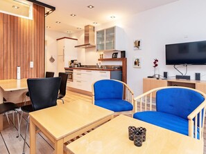 Un salon moderne comprenant un coin repas, une cuisine et un téléviseur.