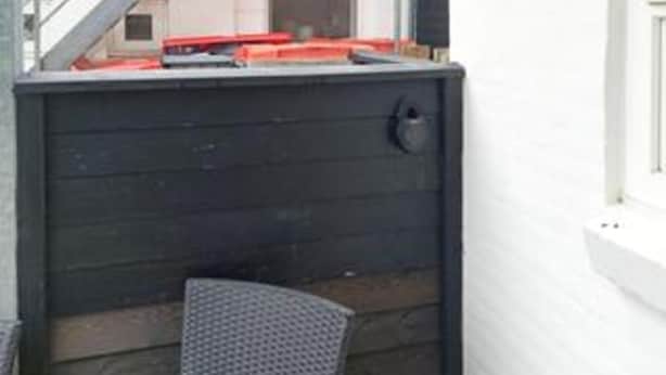 A corner of a room with a dark wooden wall, a metal door, and a small chair. - 4 Star Holiday Home in Lokken (Lokken)