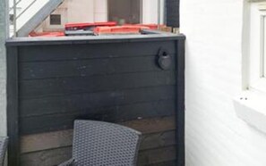 En hörna i ett rum med en mörk trävägg, en metalldörr och en liten stol.