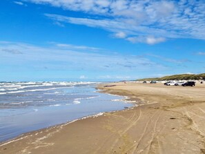 Une plage avec un rivage sablonneux, des vagues et un ciel dégagé.