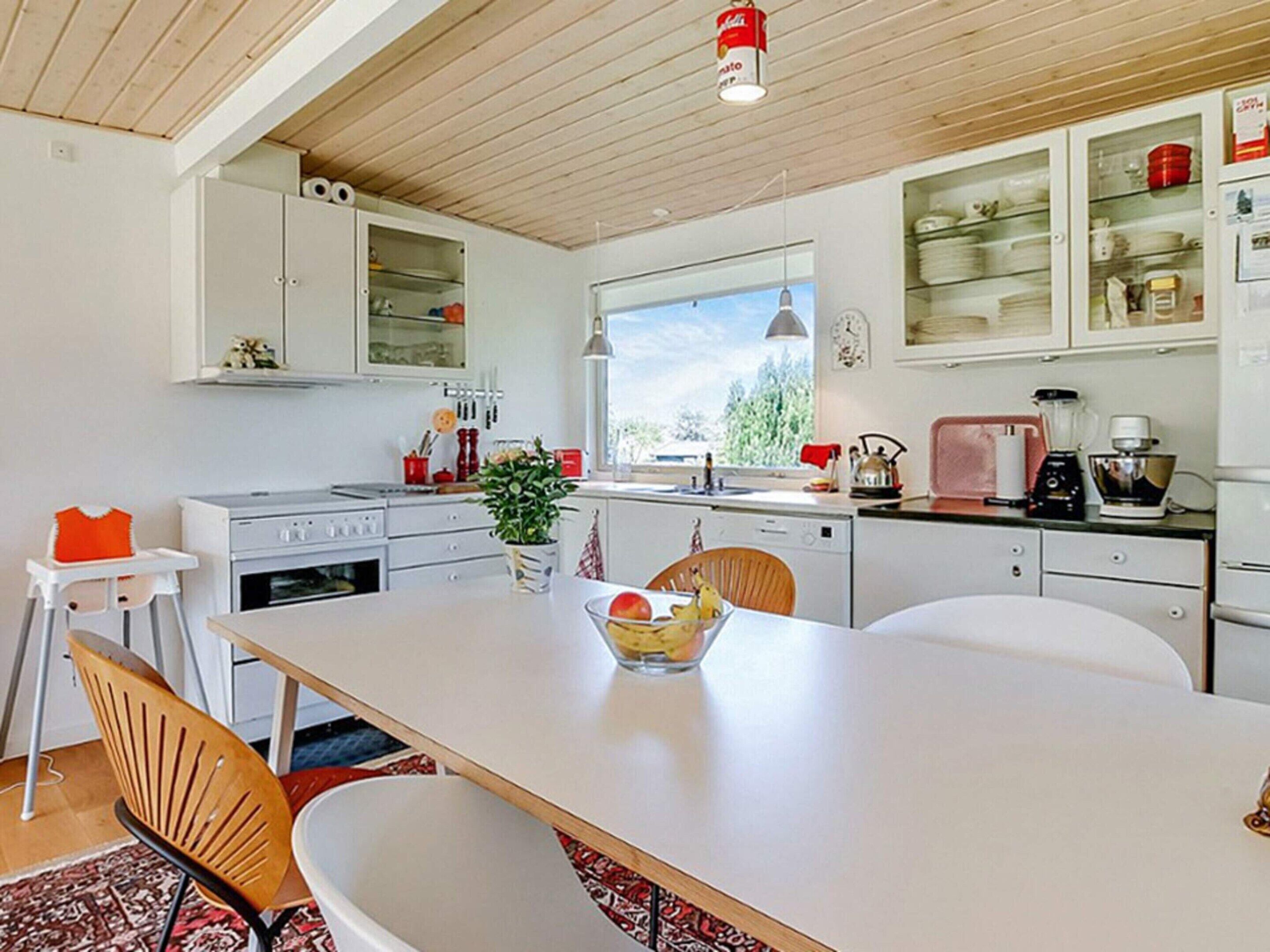 A modern kitchen with white cabinets, a dining table, and a window providing natural light.