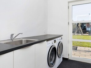A laundry room with a sink, two washing machines, and a window with a view of the outside. - 4 Star Holiday Home in Vinderup (Vinderup)