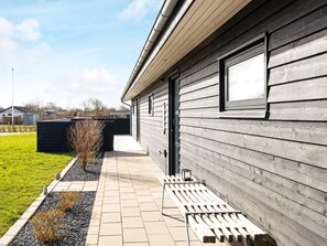 A modern building with a wooden exterior, a paved pathway, and a small garden area.