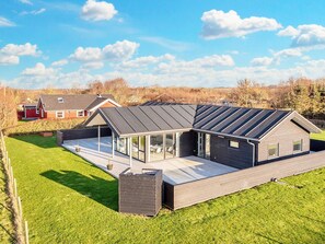 A modern house with a sloped roof, large windows, and a covered patio area. - 4 Star Holiday Home in Vinderup (Vinderup)