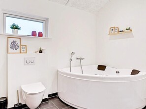 A modern bathroom with a freestanding bathtub, a toilet, and a window with a view.