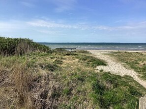 Ein Strandweg führt zu einer Bank mit Blick auf das Meer.