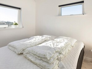 A bedroom with a bed, two windows, and a visible power outlet. - 4 Star Holiday Home in Vinderup (Vinderup)