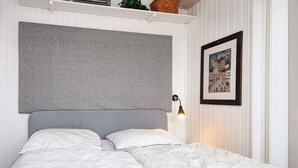 A bed with white bedding and a grey headboard, a wall-mounted light, and a framed picture. - 6 Person Holiday Home in Fano (Fano)