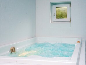 A white bathtub filled with water, a small window above it, and a wooden handle on the side. - 8 Person Holiday Home in Henne (Henne)
