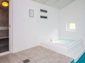 Een badkamer met een badkuip, een raam en ventilatie.