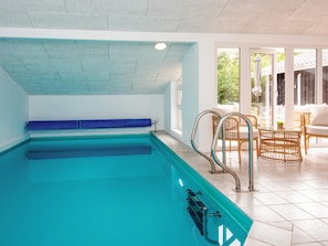 An indoor swimming pool with clear water, a blue bench, and metal handrails. - 8 Person Holiday Home in Henne (Henne)