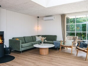 A modern living room with a green sofa, a round coffee table, and a fireplace.