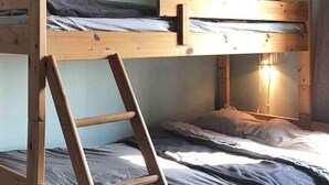 Dormitorio con literas, una mesita de noche y una lámpara fijada a la pared.
