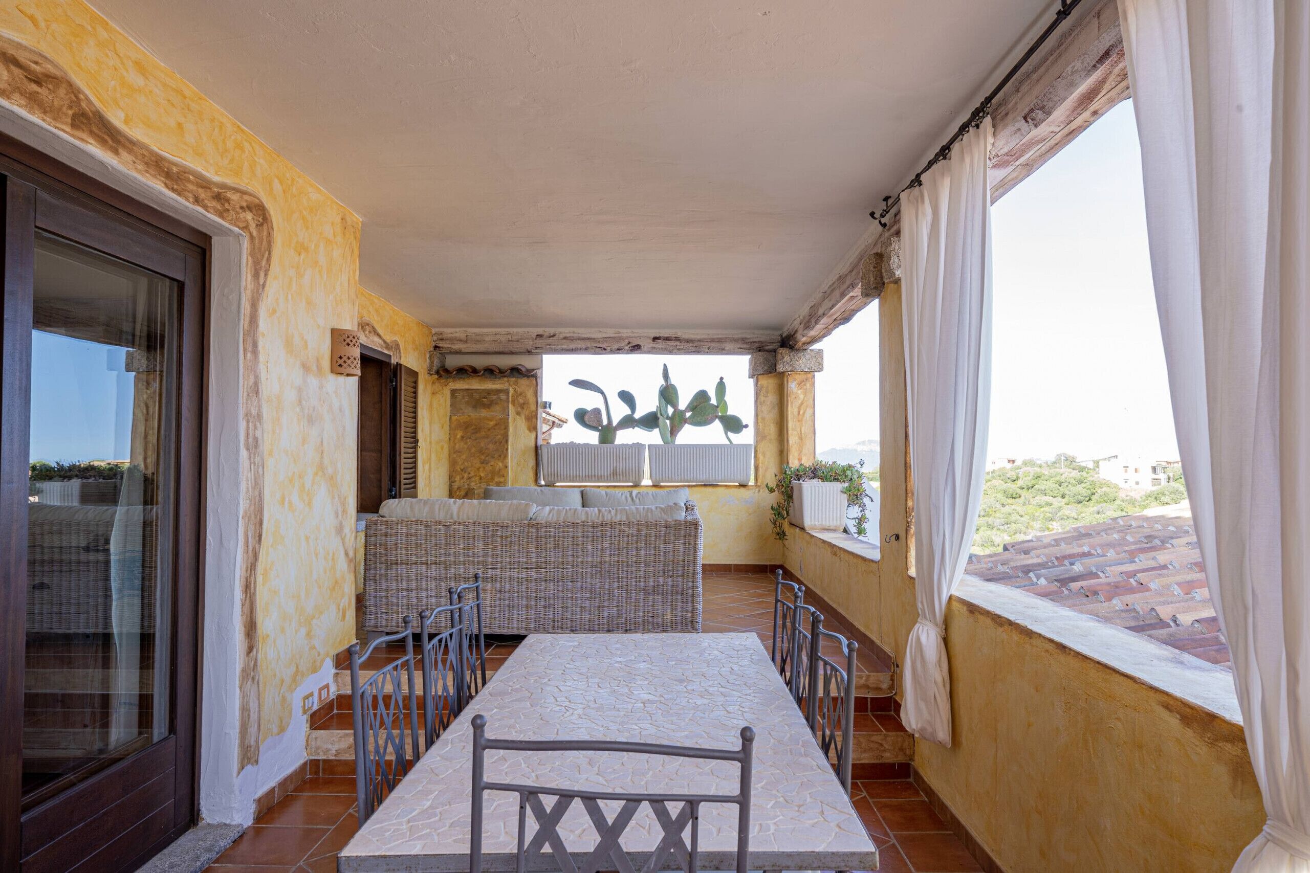 A covered patio with a table and chairs, a sofa, and a view of the city.