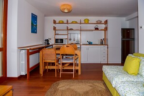Eine kleine Küche mit Essbereich, ein Bett mit gelber Bettwäsche und eine Heizung.