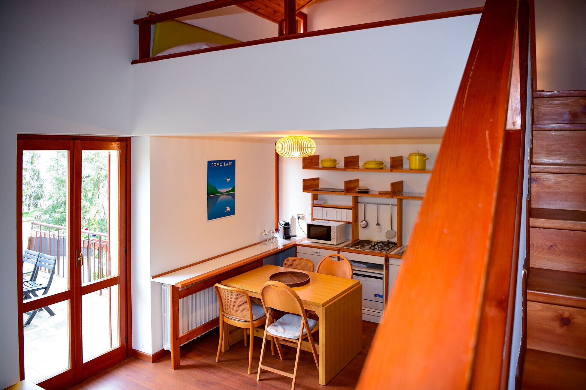 Cocina compacta con comedor, mobiliario de madera y vistas al lago Como.